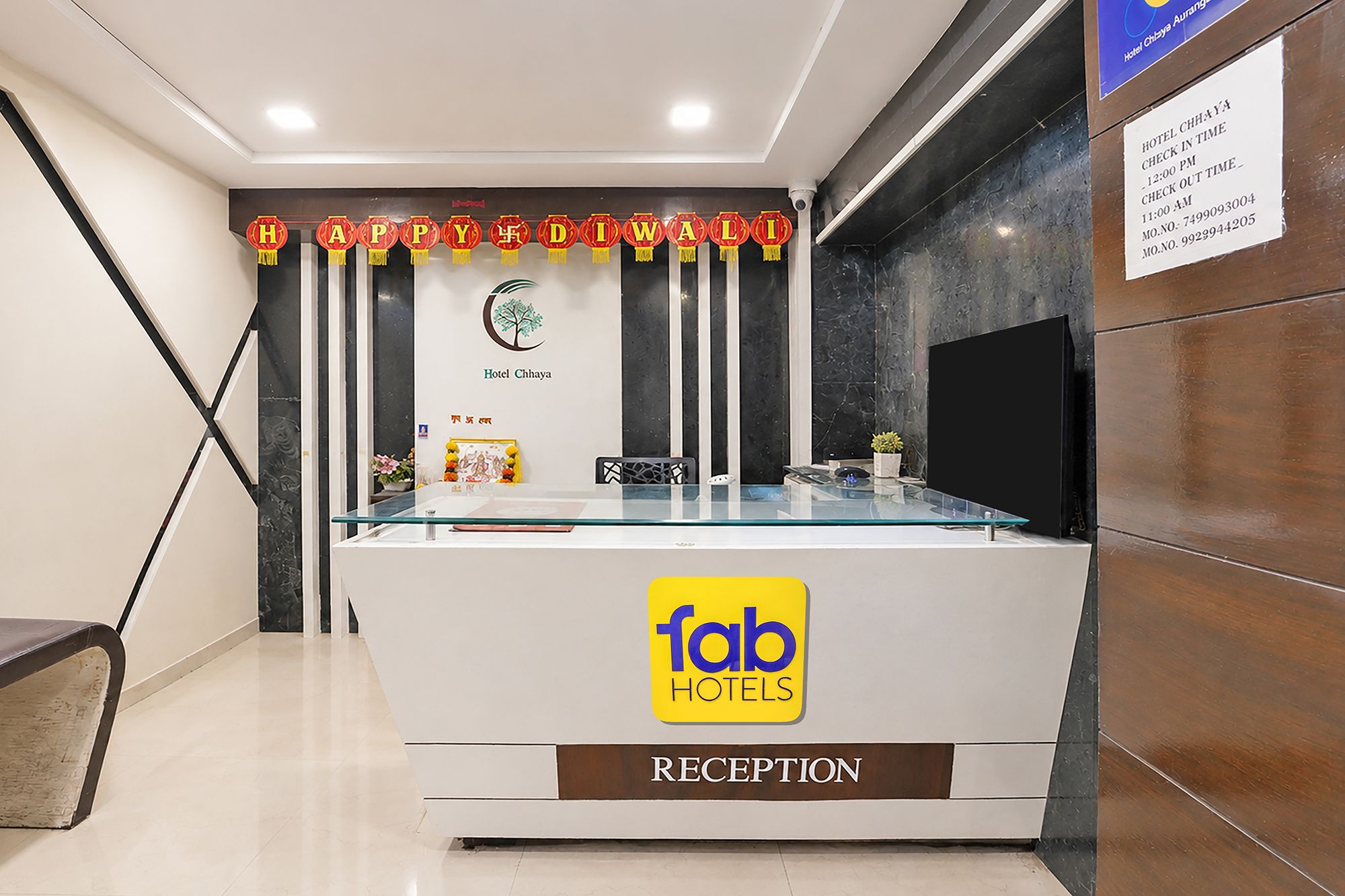 Una recepción con encimera de vidrio, el logotipo de 'fab hotels' y un letrero que indica 'Hotel Chhaya'.
