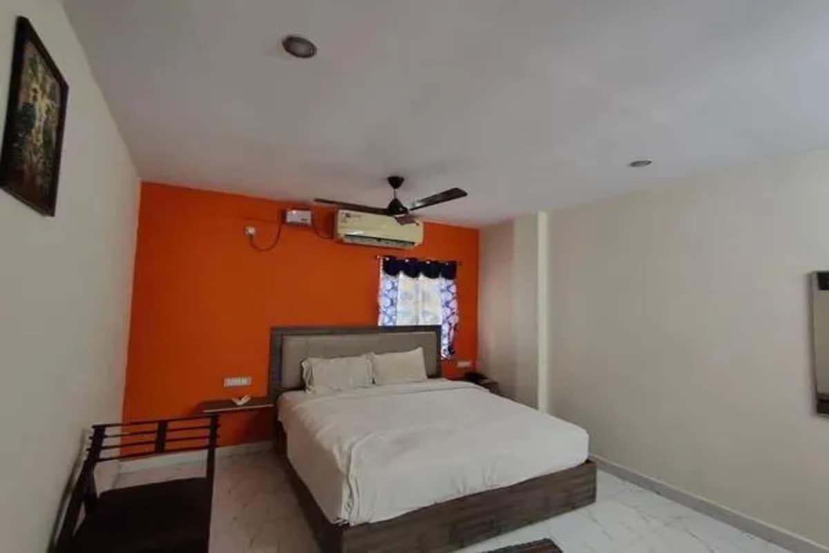A bedroom with a bed, a nightstand, a ceiling fan, and a window with curtains.