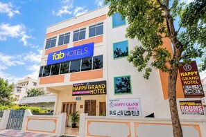 Un hotel con un cartel que dice 'Happy Grand Hotel' y 'Habitaciones con aire acondicionado, Habitaciones Deluxe'.