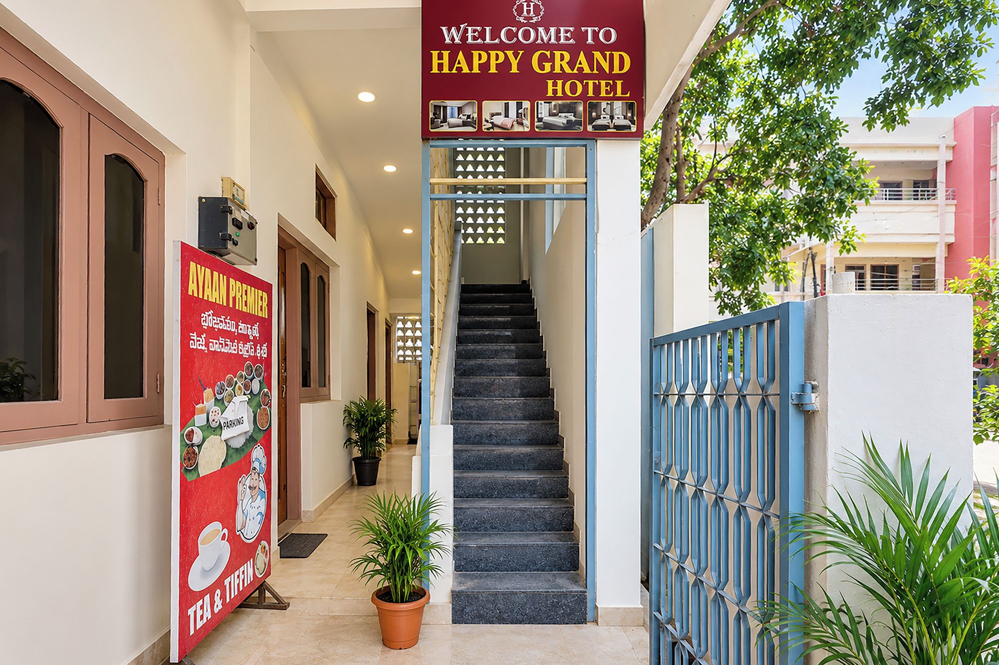 Hoteleingang mit Treppe, Willkommensschild und Schautafel, die Tee und ein Restaurant bewirbt.