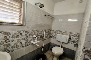 A bathroom with a toilet, a shower, and a window. - Fabhotel Happy Grand (Vijayawada)