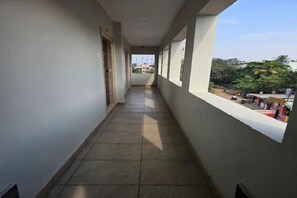 A corridor with a tiled floor, leading to a balcony with a view of the outside. - Fabhotel Happy Grand (Vijayawada)