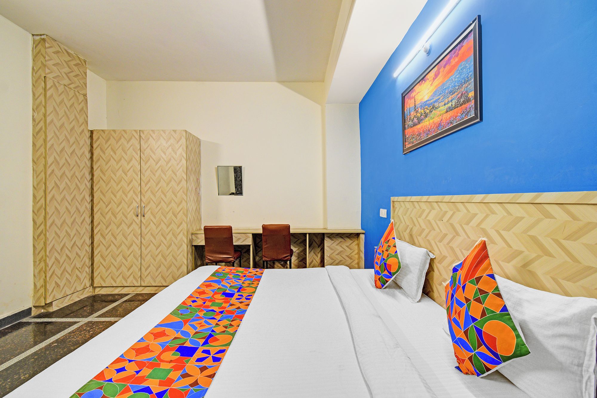 A hotel room with a bed, a desk, and chairs.