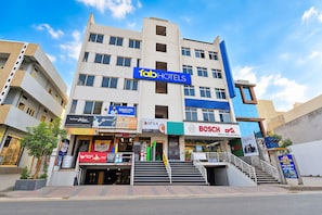 A multi-story hotel with a prominent 'Tab Hotels' sign, multiple ground-level shops, and a staircase leading to the entrance. - FabHotel Living Tree Suites (Hyderabad)