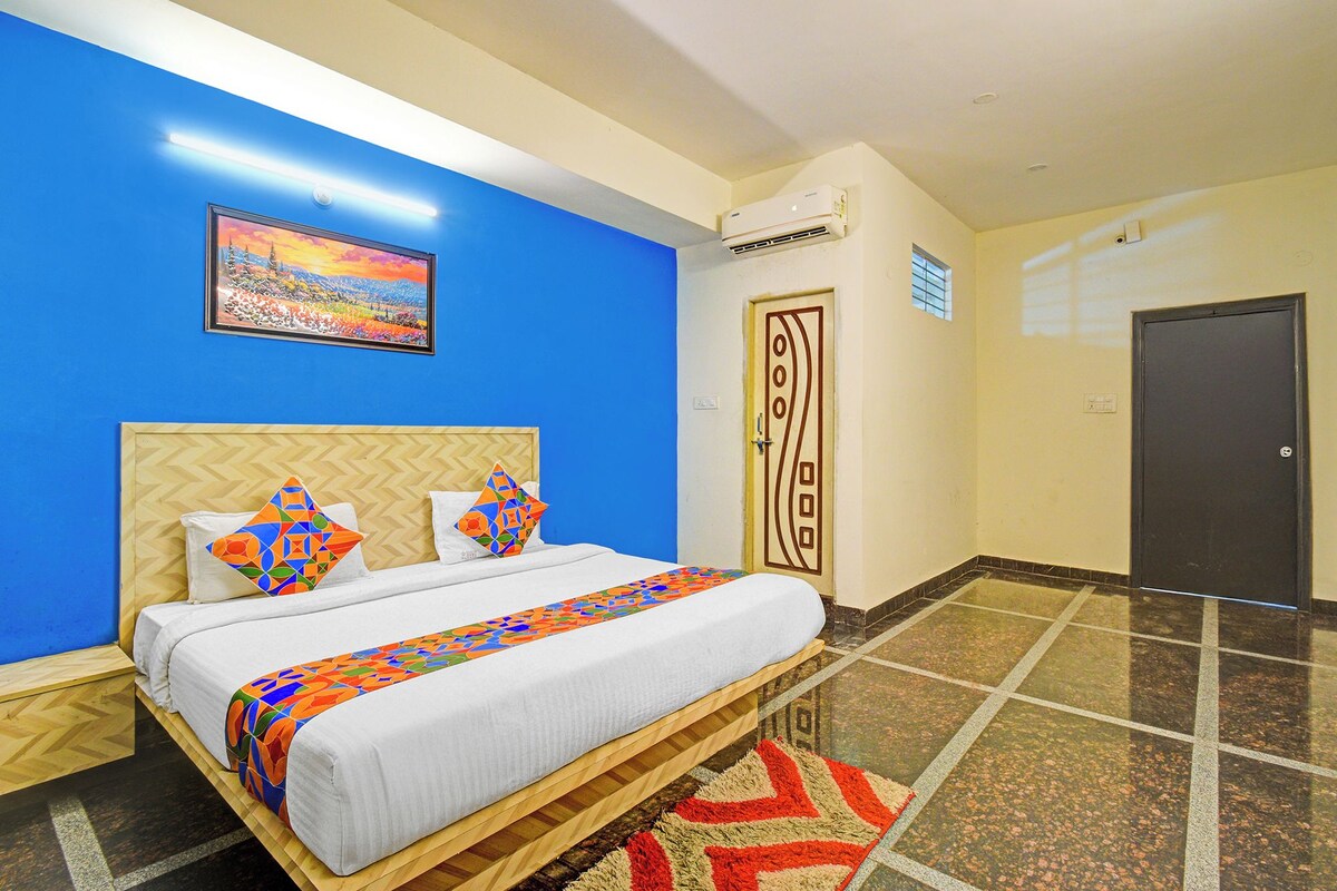 A hotel room with a bed, a painting, an air conditioning unit, and a door.