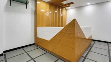 Balcão de recepção com acabamento em madeira e bancada branca.