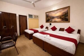 A hotel room with two beds, a desk, a chair, and a painting on the wall. - Fabhotel Cozi Inn (Gurugram)
