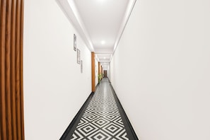 Un pasillo con suelo estampado, paredes blancas y paneles de madera en un lateral.