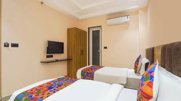 A hotel room with two beds, a TV, and an air conditioning unit.
