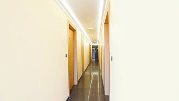 A long, narrow hotel corridor with doors on both sides and a shiny floor.