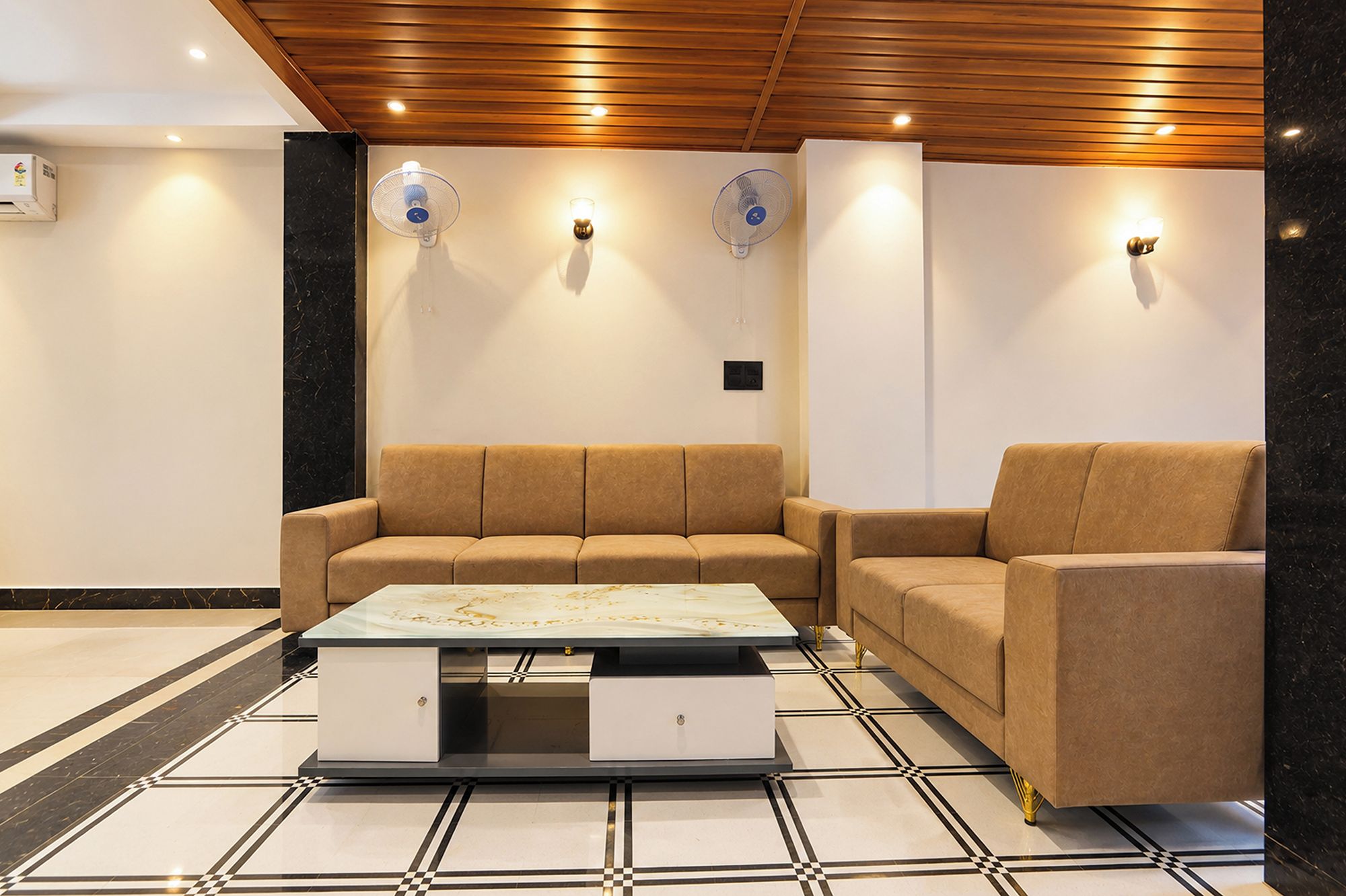 A modern living room with a sofa, a coffee table, and wall-mounted fans.