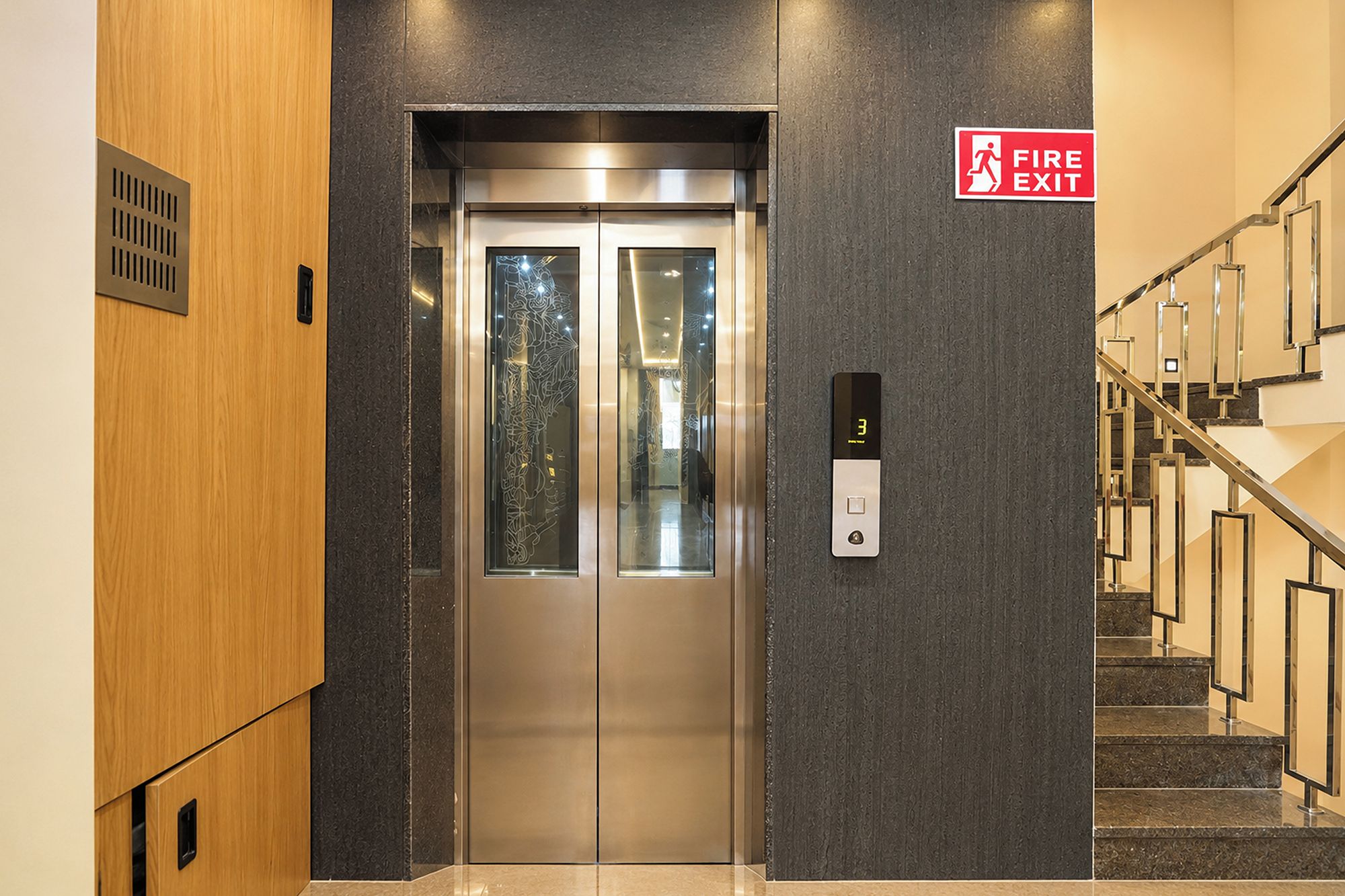 A fire exit sign, an elevator, and a staircase.
