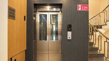 A fire exit sign, an elevator, and a staircase.