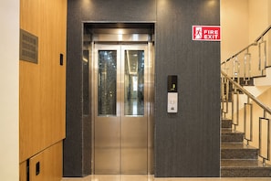 A fire exit sign, an elevator, and a staircase. - FabHotel Shri Hari Villa (Varanasi)