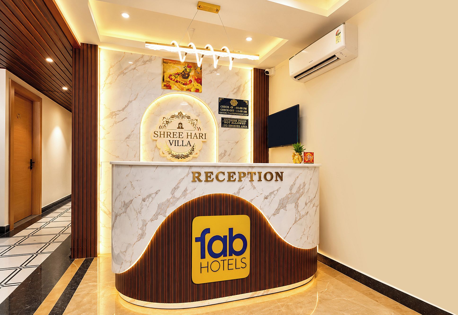 A reception desk with a marble top, a Shree Hari Villa sign, and a Faber Hotels logo.