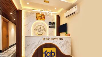 A reception desk with a marble top, a Shree Hari Villa sign, and a Faber Hotels logo.