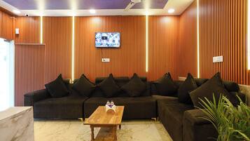 A modern living room with a sectional sofa, a wooden coffee table, and a television mounted on the wall.