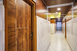 Un passadís amb portes de fusta i parets revestides de rajoles, que condueix a una habitació amb finestra.