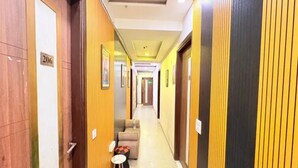 A hotel corridor with doors on either side, a sofa, and a small table. - Fabhotel Grand Vista (New Delhi)
