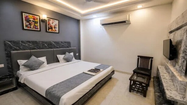 A modern bedroom with a large bed, a television mounted on the wall, and a small table. - Fabhotel Grand Vista (New Delhi)