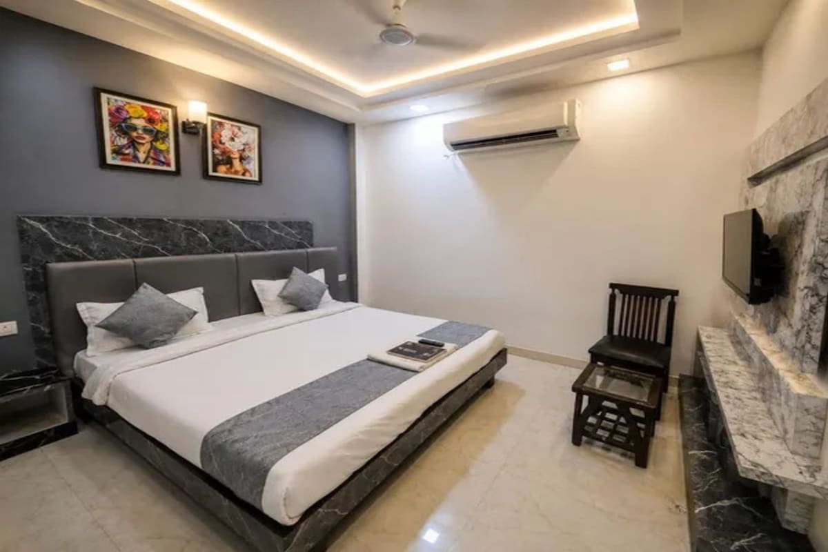 Un dormitorio moderno con una cama grande, un televisor montado en la pared y una mesita.