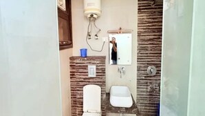 A bathroom with a toilet, sink, and a mirror. - Fabhotel Grand Vista (New Delhi)