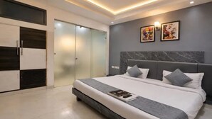 A modern bedroom with a large bed, a wardrobe, and a door with frosted glass panels. - Fabhotel Grand Vista (New Delhi)