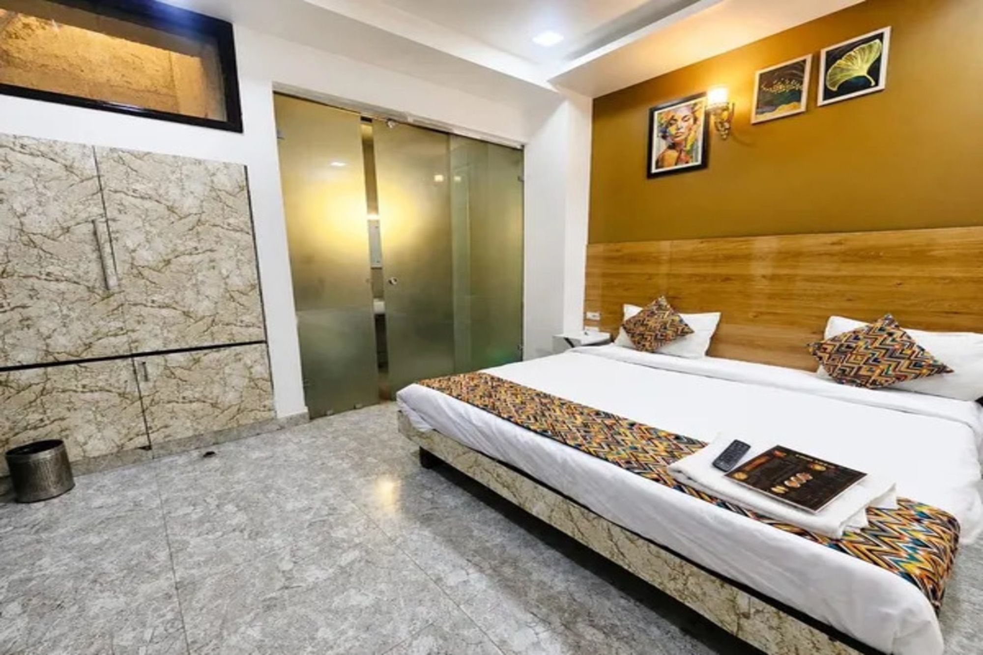 Une chambre d’hôtel avec un grand lit, une tête de lit en bois et un sol en marbre.