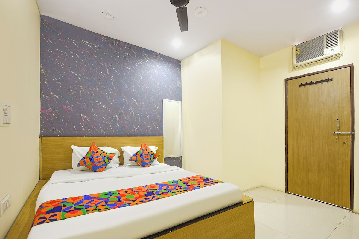 A hotel room with a bed, a wooden headboard, a large mirror, a door, and a ceiling fan.