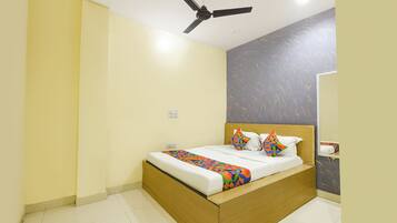 Un dormitorio con cama, ventilador de techo, pared con diseño geométrico y espejo.