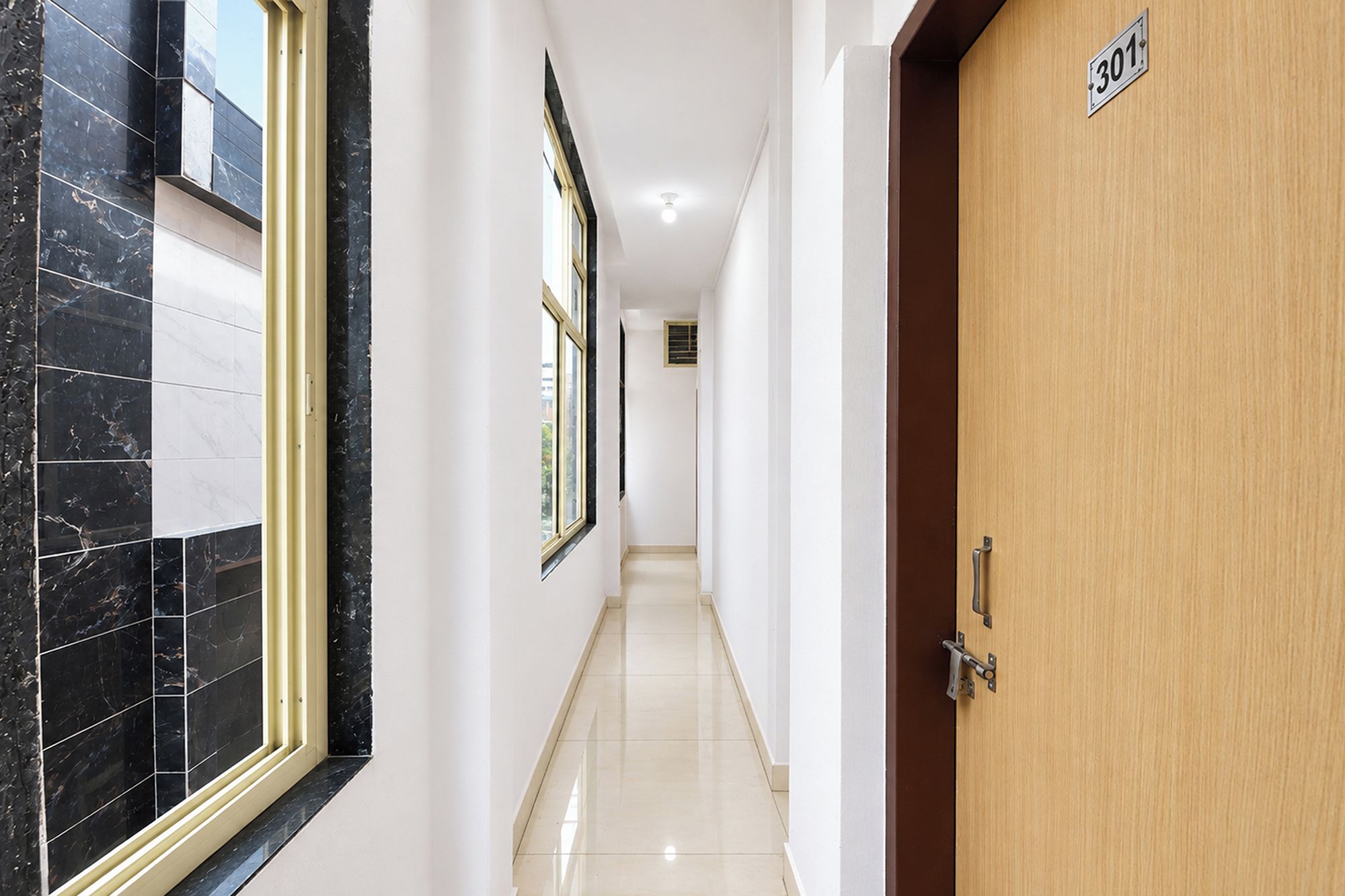 Un pasillo con una puerta de madera con la etiqueta '301', pared y suelo de baldosas.