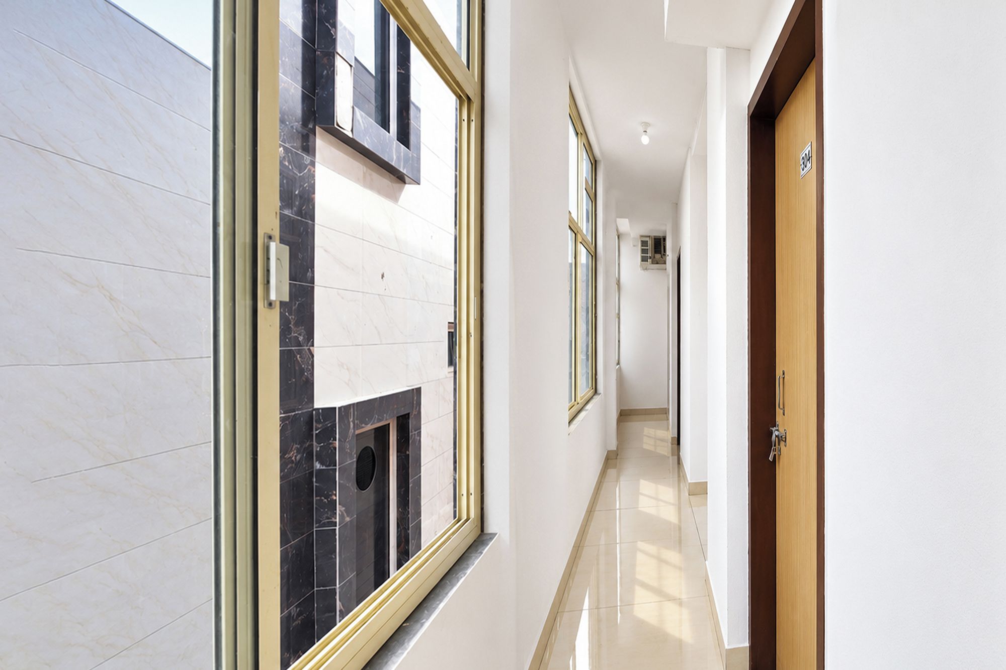 Un pasillo con pared de mármol, puerta de madera y una ventana.