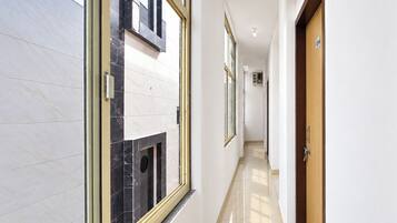 Un pasillo con pared de mármol, puerta de madera y una ventana.