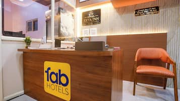 A hotel reception desk with a sign for 'fab hotels' and a check-in/out sign.