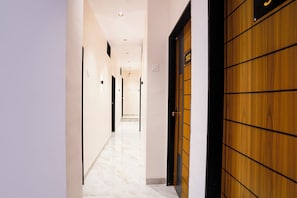 A corridor with a wooden door on the right, a number '302' sign above it, and a marble floor. - FabHotel Ekta Inn (Chhatrapati Sambhajinagar)