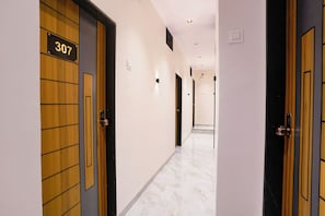 Un pasillo de hotel con puertas de madera, número 307, y piso de mármol.