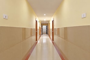 A hotel corridor with a tiled floor, doors on both sides, and a light fixture on the ceiling. - FabHotel Sgs Residency (Visakhapatnam)