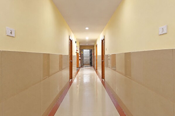 Pasillo de hotel con suelo de baldosas, puertas a ambos lados y una lámpara en el techo.