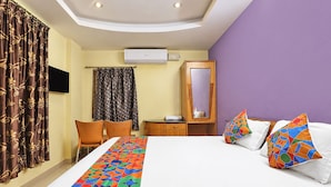 Una habitación de hotel con cama, escritorio, silla, armario y baño.