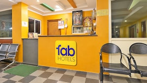 Zona de recepción de un hotel con mostrador de check-in, escritorio de recepción y un área de estar con sillas.