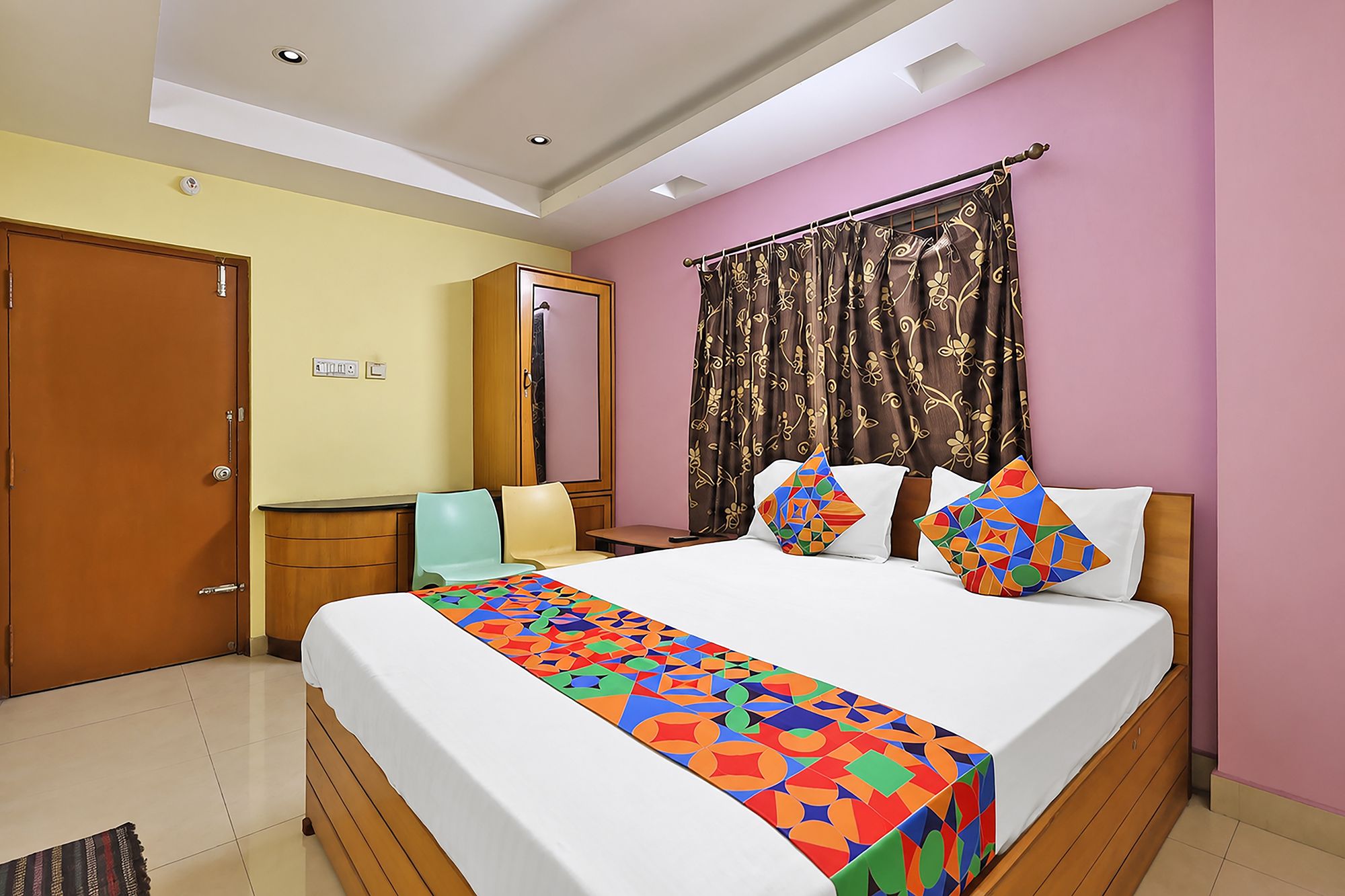 A hotel room with a bed, a desk, a chair, a wardrobe, and a bathroom door.