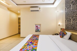 Habitación de hotel con cama, un cuadro, pared con diseño y un equipo de aire acondicionado.