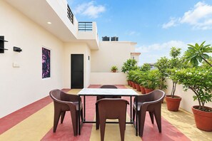 Una terrazza sul tetto con un tavolo, sedie, piante in vaso e una porta.