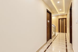 Un corridoio d'hotel con pavimento in marmo, porte in legno e una scala.