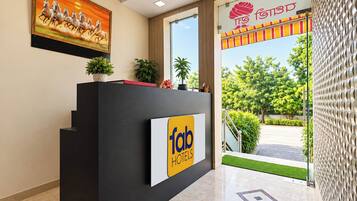 Mostrador de recepción de hotel con un cartel que dice 'Tap Hotels' y un ventanal que ofrece vistas al verde exterior.
