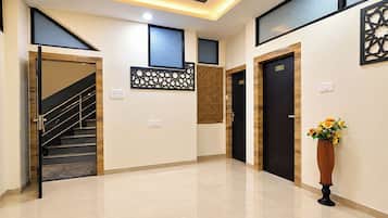 Vestíbulo de hotel con escalera, mostrador de recepción y un panel decorativo en la pared.