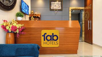 A reception desk with a 'fab hotels' sign, a clock, a television, and a decorative item on the wall.