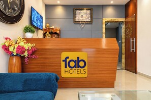 A reception desk with a 'fab hotels' sign, a clock, a television, and a decorative item on the wall. - Fabhotel Shivom (Indore)
