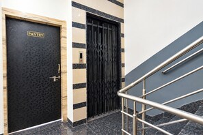 Une porte noire avec une pancarte indiquant « GARDEMANGER », une grille de sécurité en métal et un escalier avec des rampes en métal.