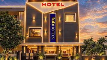 A modern hotel building with a prominent 'HOTEL' sign, a vertical 'HOTEL' banner, and a well-lit entrance.